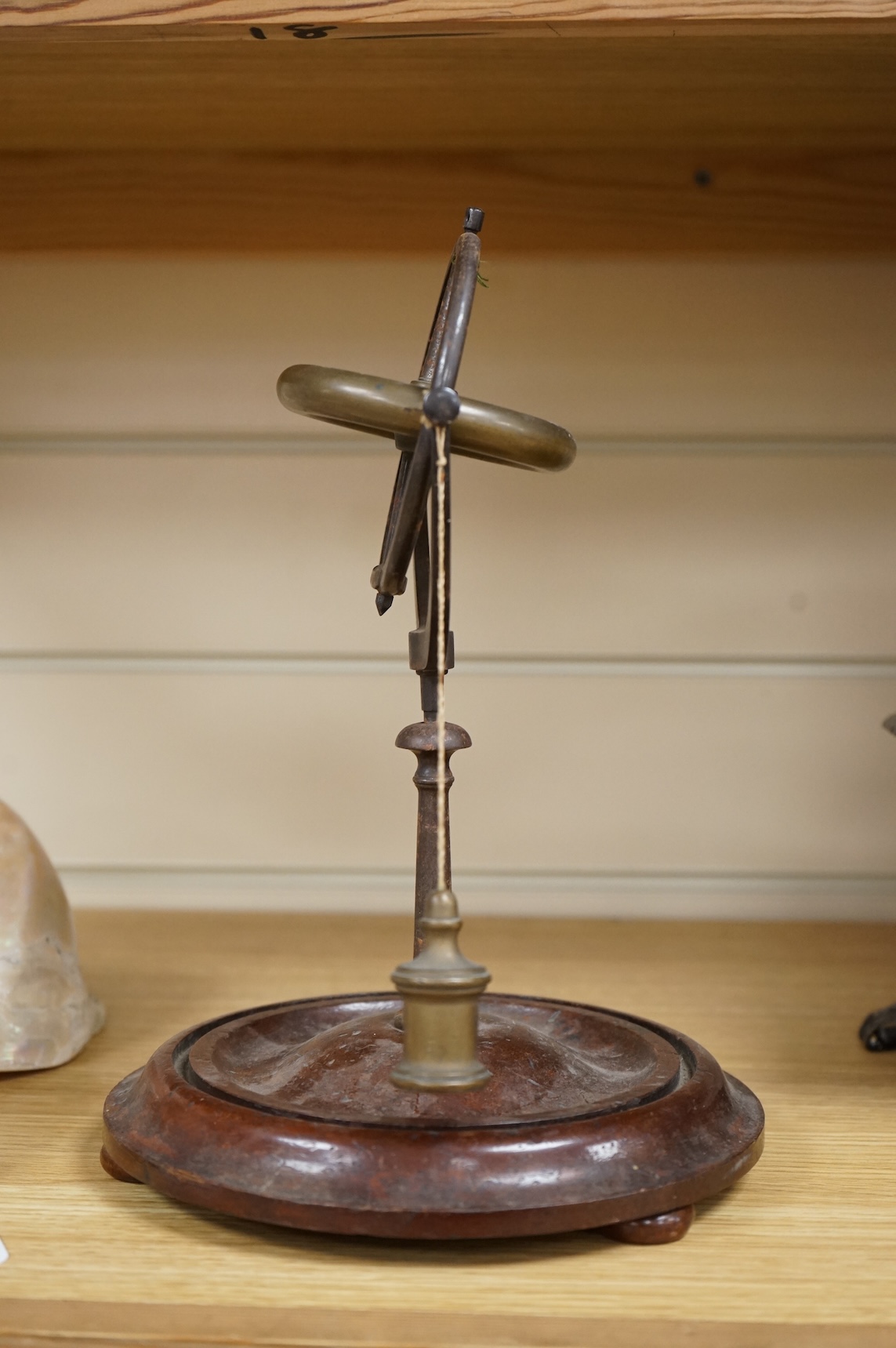 A 19th century brass gyroscope on a turned mahogany base, 26cm high.
